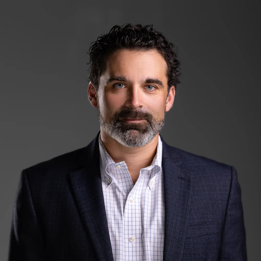 Executive headshot in navy blazer on gray backdrop